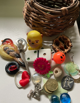 Basket with contents displayed including various toys, bits of jewelry and dominoes